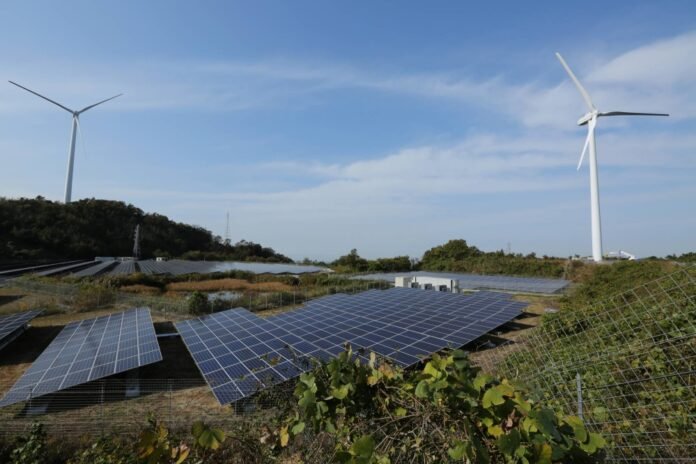 Wind turbines stand next to solar panels at a solar plant in Awaji, Hyogo Prefecture. Japan's energy plan under a review is expected to call for raising the renewable energy sources in the power mix. 