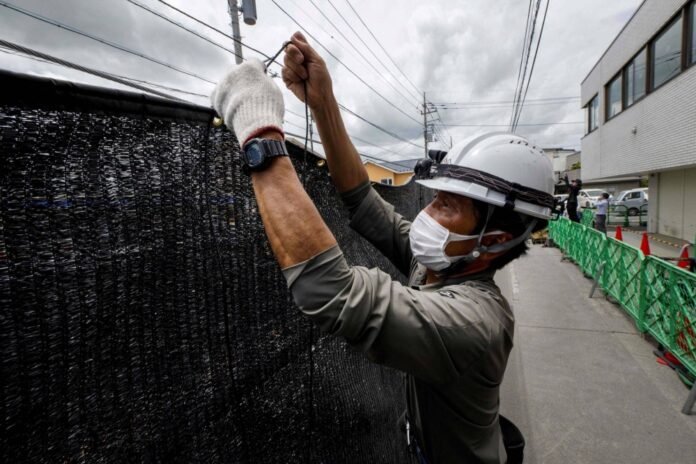 A worker installs a barrier to block the sight of Mount Fuji in the town of Fujikawaguchiko, Yamanashi Prefecture, on May 21. 