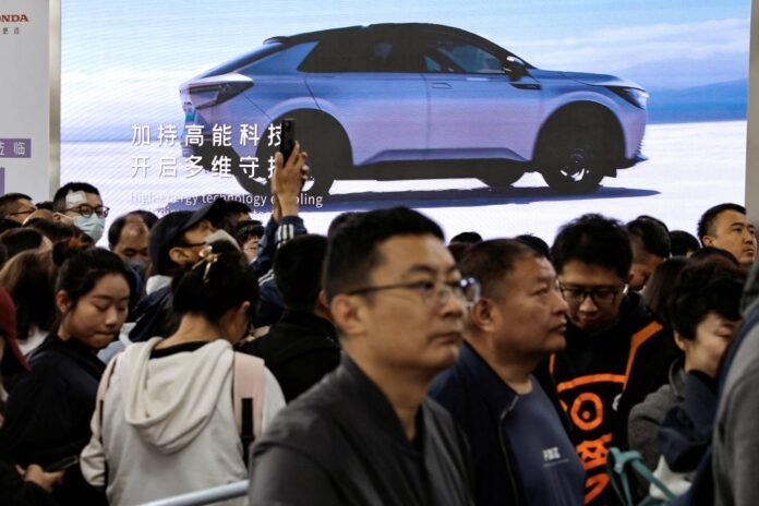Visitors line up near a billboard for a Honda electric vehicle at the Beijing International Automotive Exhibition in Beijing in April. 