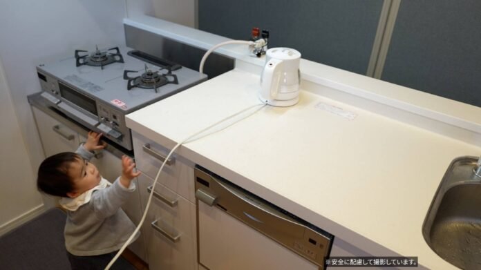 A toddler tries to pull an electric kettle cord. Parents can often recognize the dangers within their own home, but may not be as vigilant when visiting new places during the holidays. 