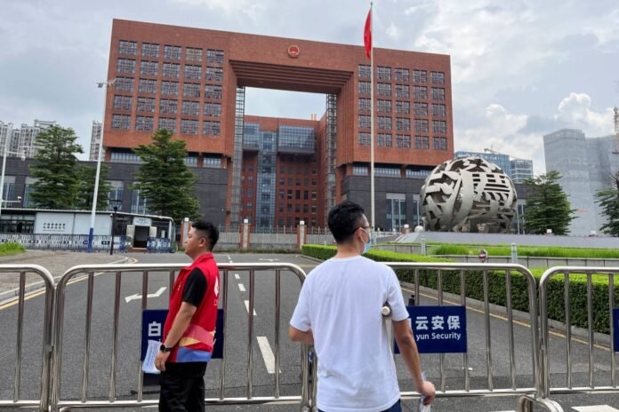 People stand outside the Guangzhou Intermediate People's Court, where #MeToo activist Huang Xueqin and labor activist Wang Jianbing were sentenced, in Guangzhou, Guangdong province, China, on Friday. 