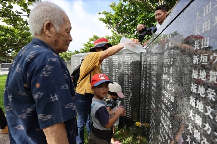 A man visits the Cornerstone of Peace, a monument in the Peace Memorial Park in Itoman, Okinawa Prefecture, with his family, including his great-grandchildren, on Sunday, the 79th anniversary of the end of the Battle of Okinawa. 