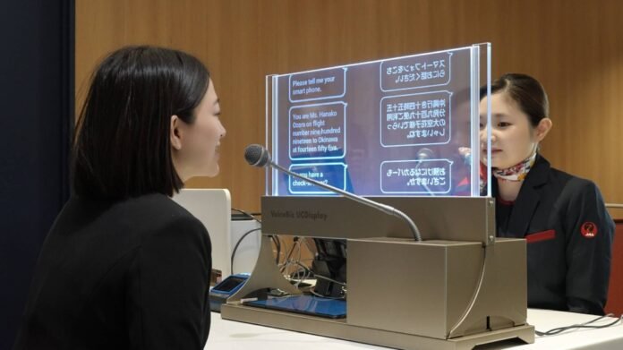 A demonstration of a clear-screen translation system is conducted at a counter at Haneda Airport in Tokyo on Tuesday. 