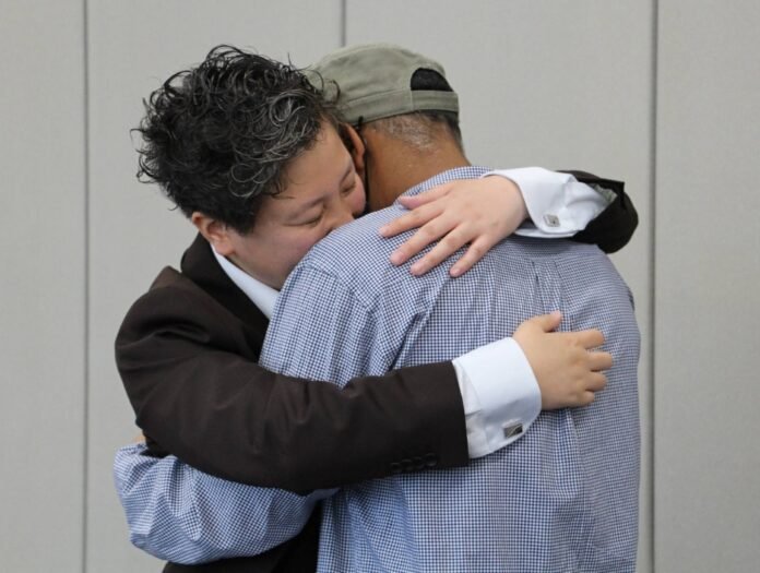 A man from North Africa (right) embraces his lawyer after a verdict was handed down Osaka District Court revoking a decision by immigration authorities not to grant him refugee status, in Osaka on Thursday. 