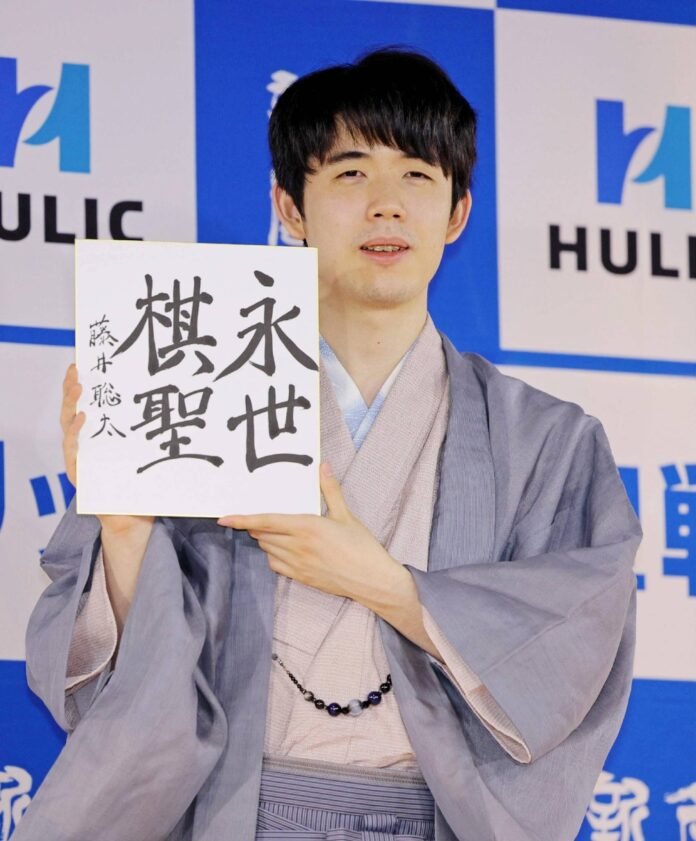 Shogi star Sota Fujii holds a board with his new title "eisei Kisei" after a match in Nagoya on Monday. 