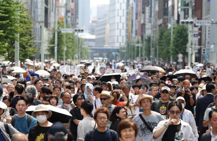 People gather to listen to a campaign speech in Tokyo amid the heat Saturday, ahead of the capital's gubernatorial election the following day. 